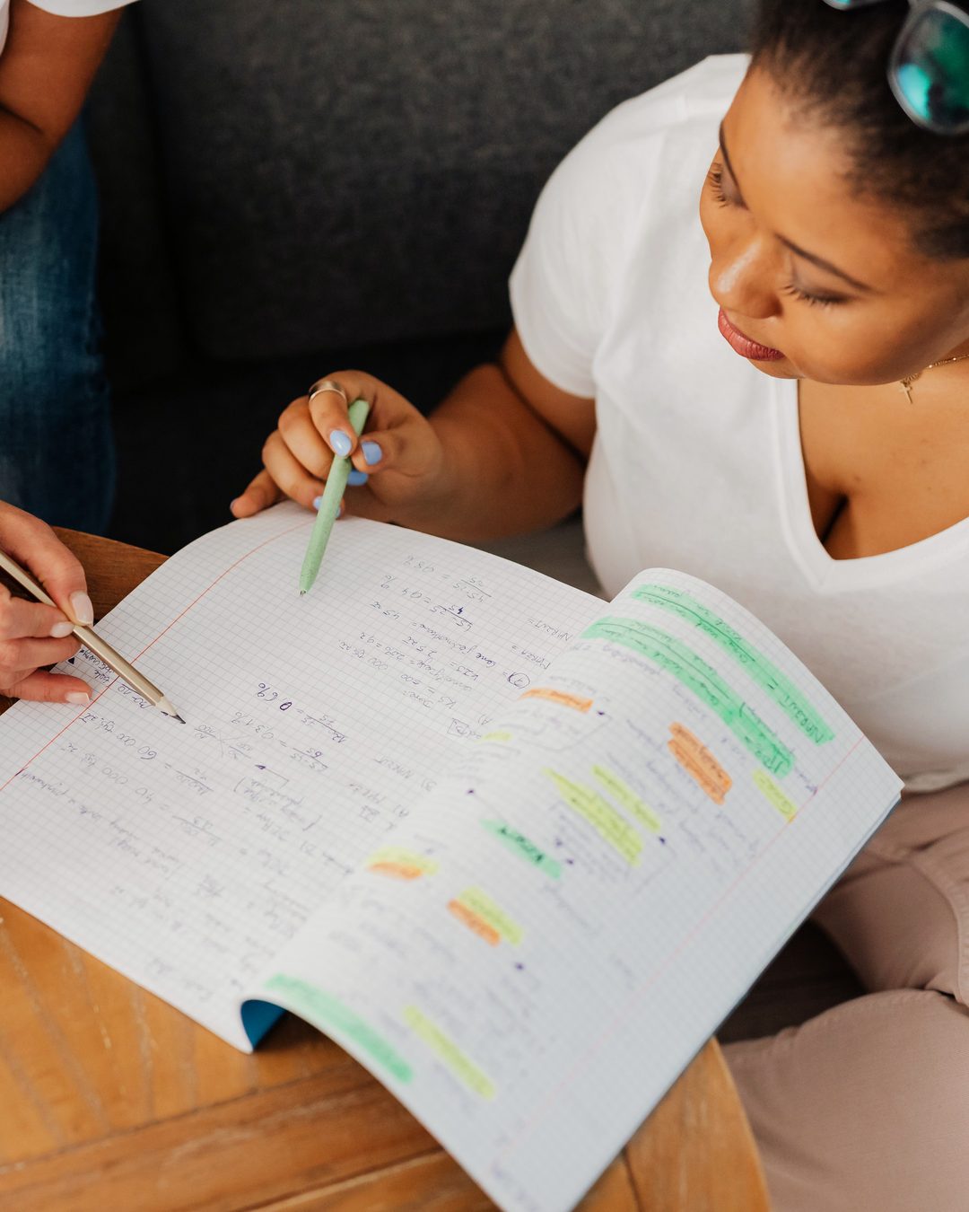 Overhead view of a tutor and student going through highlighted revision notes in an exercise book